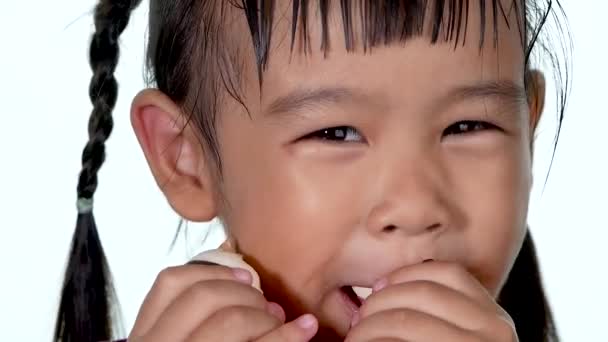 かわいい女の子が甘いドーナツを食べ 白い背景の上に味を楽しむのクローズアップビュー — ストック動画