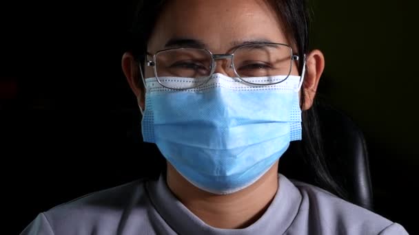 暗い背景でコロナウイルスの流行 Pm20 大気汚染 から彼女を守るために医療面のマスクを身に着けて 眼鏡をかけた自信アジアの女性の肖像画を閉じます 新しい正常な行動 — ストック動画