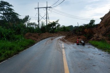 Şiddetli yağış sonrasında eğimli bir dağ yolunu kaplayan toprak ve kayalarla dolu heyelan, trafik ve tehlikelere yol açıyor.
