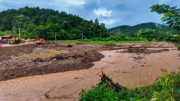 Enkaz ve ağır makinelerle dolu çamurlu bir nehir akıntısı kurtarma çabaları üzerinde çalışıyor..