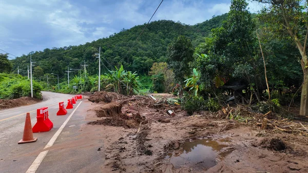 Şiddetli yağmurun ardından güvenlik için koni ve bariyerler konan sel ve heyelan ile aşınmış hasarlı bir dağ yolu.