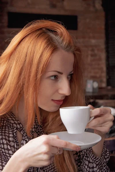 Beautiful girl drinking coffee at the bar. A seductive view of a neighbor at the table