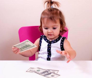 Mutlu küçük kız bizi elinde dolar tutar. Bağlam - para herkes tarafından gereklidir