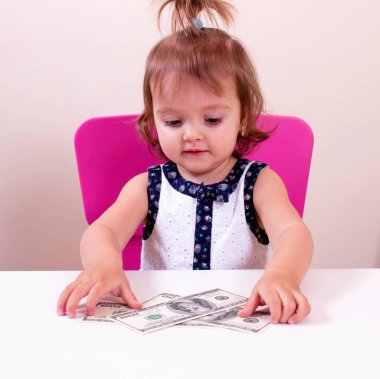 Mutlu küçük kız bizi elinde dolar tutar. Bağlam - para herkes tarafından gereklidir