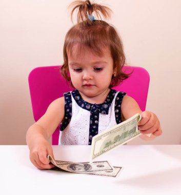 Mutlu küçük kız bizi elinde dolar tutar. Bağlam - para herkes tarafından gereklidir