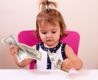 Mutlu küçük kız bizi elinde dolar tutar. Bağlam - para herkes tarafından gereklidir