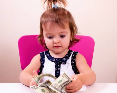 Mutlu küçük kız bizi elinde dolar tutar. Bağlam - para herkes tarafından gereklidir