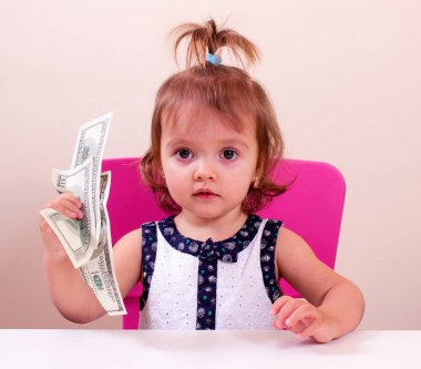 Mutlu küçük kız bizi elinde dolar tutar. Bağlam - para herkes tarafından gereklidir