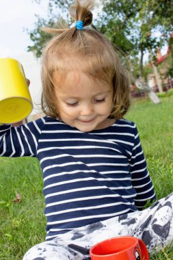 Küçük kız meyve suyu bir özsuyu ile çim üzerinde dinleniyor