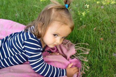 Küçük kız yeşil çimenlerin üzerinde dinlenme