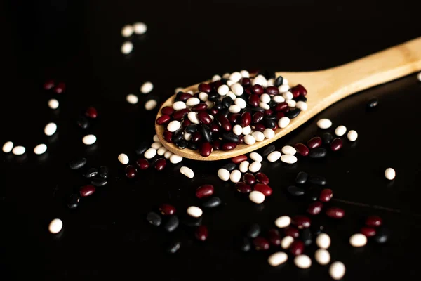 Assortment of beans and lentils in wooden spoon on wooden background. mung bean, groundnut, soybean, red kidney bean , black bean ,red bean and brown pinto beans .