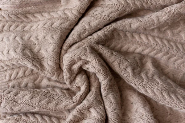 Merino wool handmade knitted large blanket, super chunky yarn, trendy concept. Close-up of knitted blanket, merino wool background. designer blanket made of beige smoky wool.
