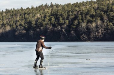 Yaşlı adam bir doğal göl donmuş buz pateni. Güzel kış günü.
