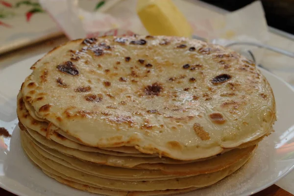 Panqueques frescos y calientes cuidadosamente apilados uno en el otro, en un plato blanco . — Foto de Stock