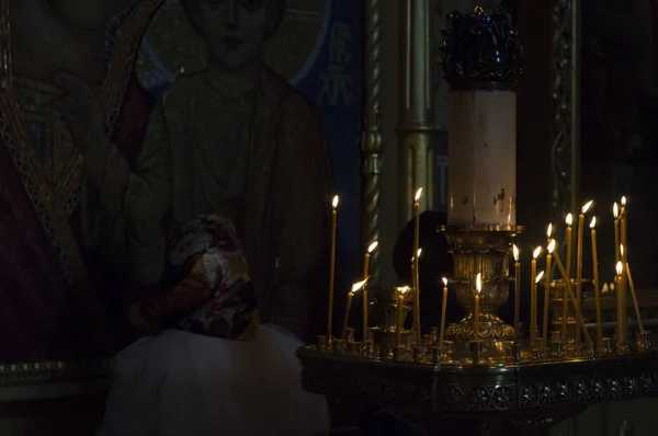 Prayer near the icon in the light of many lit church candles — Stock Photo, Image