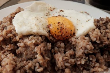 Beyaz plaka üzerinde kızarmış yumurta ile karabuğday lapası