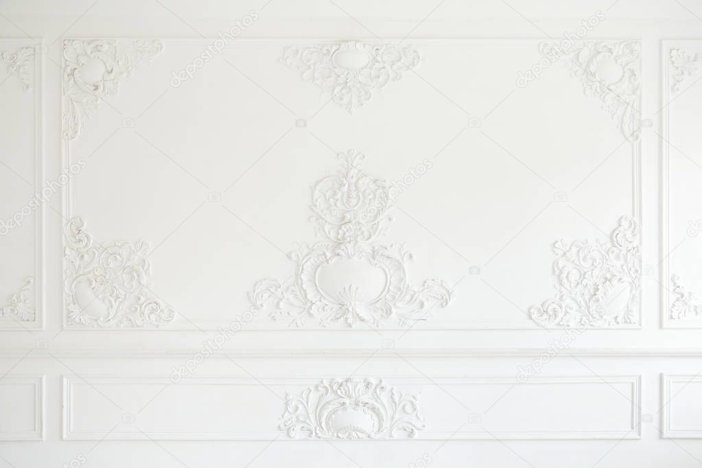 Beautiful ornate white decorative plaster mouldings in studio. The white wall is decorated with exquisite elements of plaster stucco.