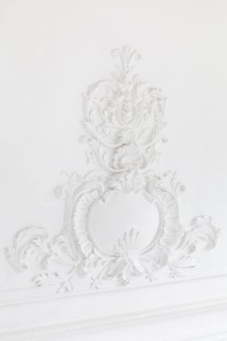 Süslü beyaz dekoratif alçı döşemeler stüdyoda. Beyaz duvar, alçı alçı kaplamasının zarif elementleriyle süslenmiş.