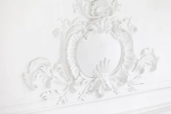 Piękne ozdobne białe ozdobne formy gipsowe w studio. Biała ściana ozdobiona jest wykwintnymi elementami gipsowego stiuku — Zdjęcie stockowe