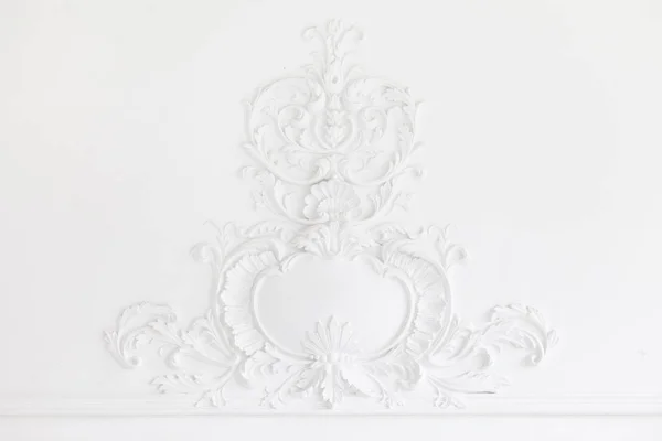 Piękne ozdobne białe ozdobne formy gipsowe w studio. Biała ściana ozdobiona jest wykwintnymi elementami gipsowego stiuku — Zdjęcie stockowe