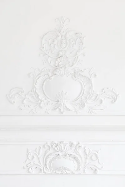 Beautiful ornate white decorative plaster mouldings in studio. The white wall is decorated with exquisite elements of plaster stucco Royalty Free Stock Images
