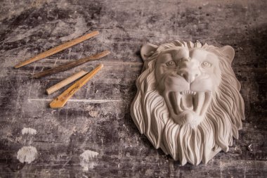 Creation of sculpture from plaster. Lions head. Plaster workshop. Tooling. clipart