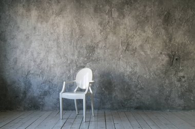 Beton duvar arka plan üzerinde beyaz plastik sandalye. Çatı katı odası. Ahşap zemin. gün ışığı. Metin için boş alan.