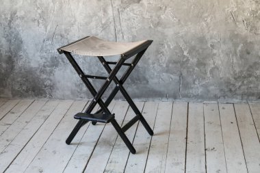 Beton duvar zemin üzerine kurulu sandalye. Çatı katı odası. Ahşap zemin. Gün ışığı. Metin için boş alan.