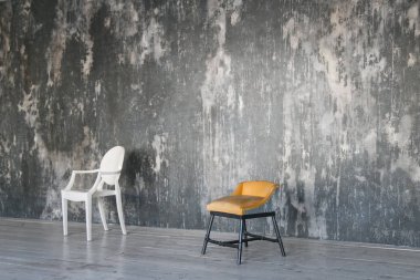 İki sandalye gri beton duvara karşı. Oda çatı katı tarzında. Ahşap zemin. Gün ışığı. Metin için boş alan.