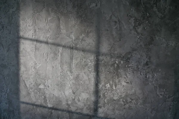 Decorative plaster. Artificial concrete. The texture of the gray concrete wall with a glint of light from the window.