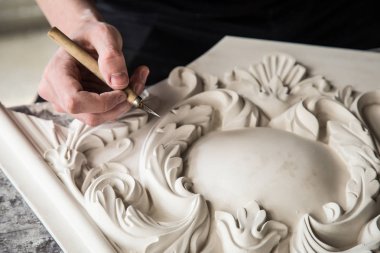 Heykeltraşın elleri aletle. Heykeltıraş stüdyoda çalışıyor. Alçıdan dekoratif bir element yaratmak. Barok tarzında lüks bir sıva. Kapatın. Seçici odak.