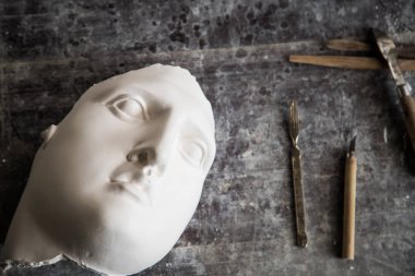 Masadaki heykeltıraşın aletleri. Apollos'un yüzü. Yukarıdan manzara. Metin için boş alan.