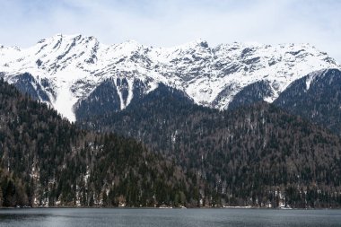 İlkbaharda Abhazya'daki Ritsa Gölü. Dağın tepelerini karla kaplıdır. Turizm sezonunun başlangıcı.