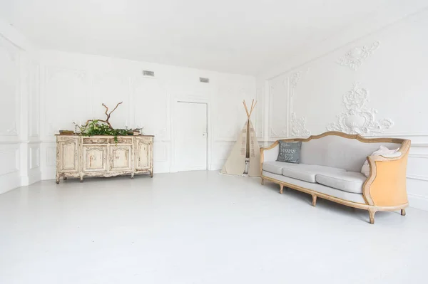 壁、ソファ、ウィグワム、植物で飾られた引き出しの胸にスタッコと部屋の豪華な光のインテリア. — ストック写真