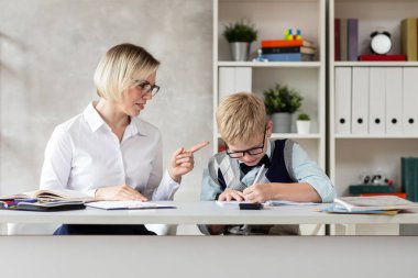 Genç bir öğrenci ve kendine güvenen öğretmeni masaya oturur ve bir dikte yazar..