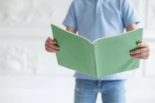 Encerramento do livro verde nas mãos do menino em t-shirt azul — Fotografia de Stock