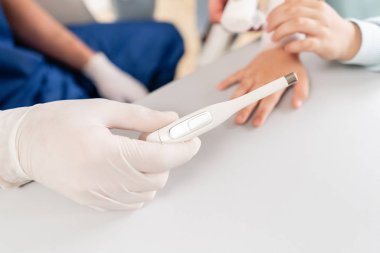 Erkek kolu yüksek sıcaklık gösteren elektronik termometre tutun. Hastanede çocuk doktoru