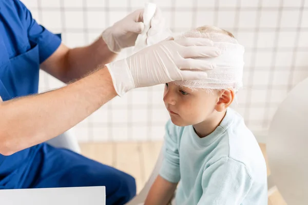Spor sakatlığı. Doktor hastanede baş hasta üzerinde bandaj yapar.