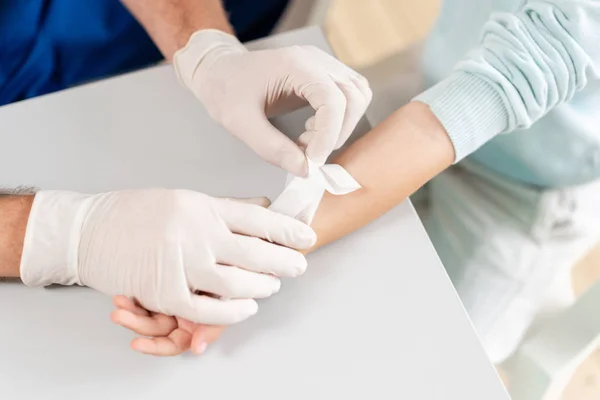 Spor sakatlığı. Doktor hastanede baş hasta üzerinde bandaj yapar.
