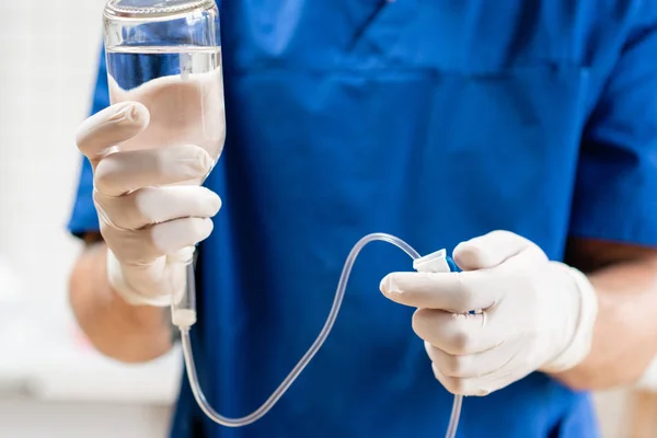 Doctor en uniforme azul sosteniendo goteo iv y bomba de infusión,. Líquido intravenoso para pacientes graves en la sala de urgencias del hospital. Tratamiento médico concepto de emergencia . —  Fotos de Stock