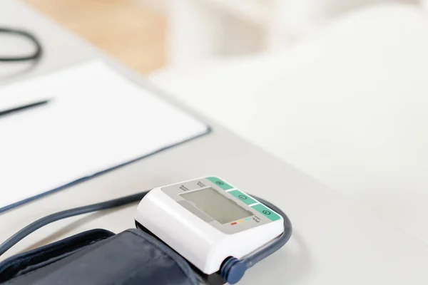 Luogo di lavoro del medico con computer portatile, stetoscopio e notebook su tavolo in legno in ufficio. Monitoraggio della pressione sanguigna. Attrezzature mediche. Diagnosi cardiaca. tono vintage . — Foto Stock