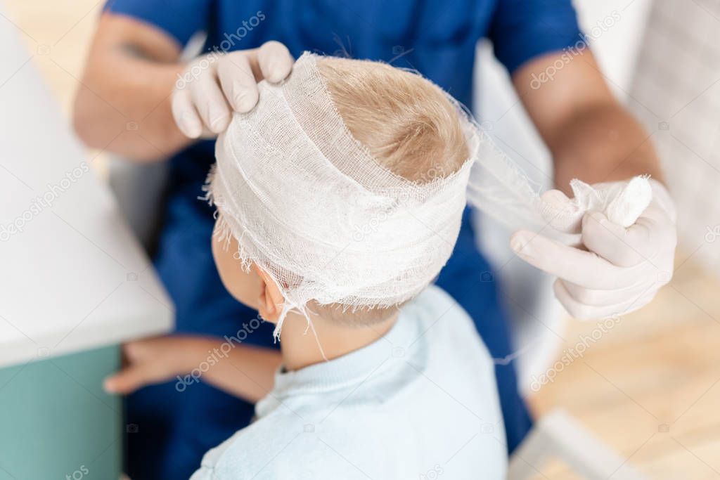 Sports injury. Doctor makes bandage on head patient, in the hospital.