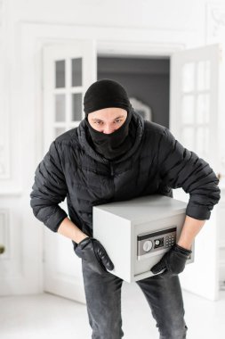 Hırsız siyah Balaclava modern elektronik güvenli kutu çalmak ile kamera bakıyor. Hırsız lüks dairede alçı ile bir suç tamamlar.