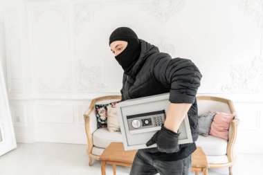 Hırsız, lüks dairede alçı ile bir suç işlemiştir. Siyah Balaclava ile Thief modern elektronik güvenli kutu çalmak.