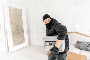 Siyah Balaclava ile Thief modern elektronik güvenli kutu çalmak. Hırsız lüks dairede alçı ile bir suç tamamlar.