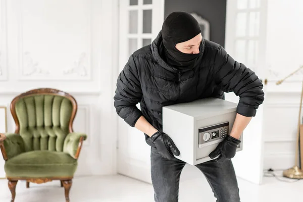 Siyah Balaclava ile Thief modern elektronik güvenli kutu çalmak. Hırsız lüks dairede alçı ile bir suç tamamlar.