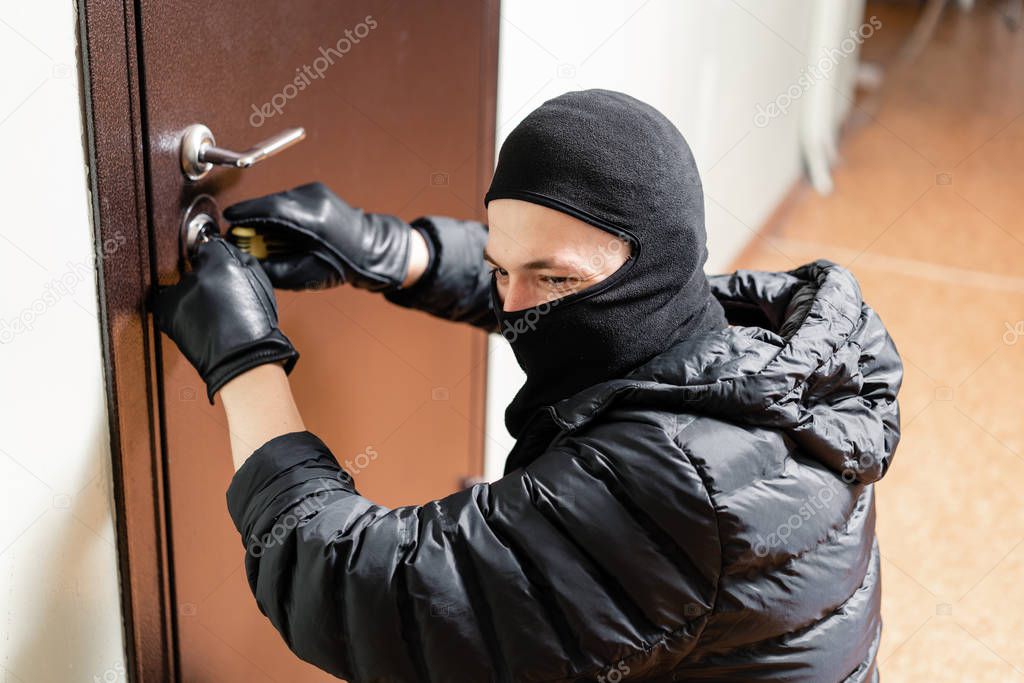 Burglar entering front door of the apartment after successfully picking the lock.