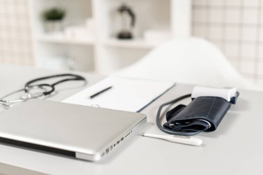 Ofiste ahşap masa üzerinde dizüstü bilgisayar, stetoskop ve dizüstü bilgisayar ile doktor İşyeri. Kan basıncı monitörü. Tıbbi ekipmanlar. Kardiyak tanı. vintage sesi.