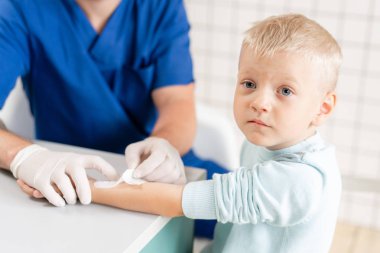 tıbbi yama. Doktor kolunda travma olan bir çocuk elini bandajladı. Elastik elinin etrafında sargılı