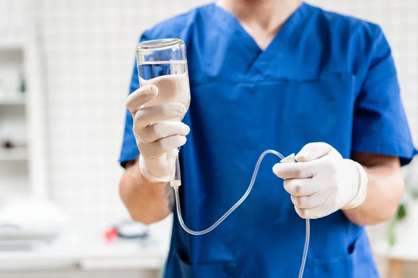 Doktor mavi üniformalı, damla iv ve infüzyon pompası tutuyor. Tıbbi tedavi acil kavram... Hastanede acil serviste ciddi hasta için intravenöz sıvı.
